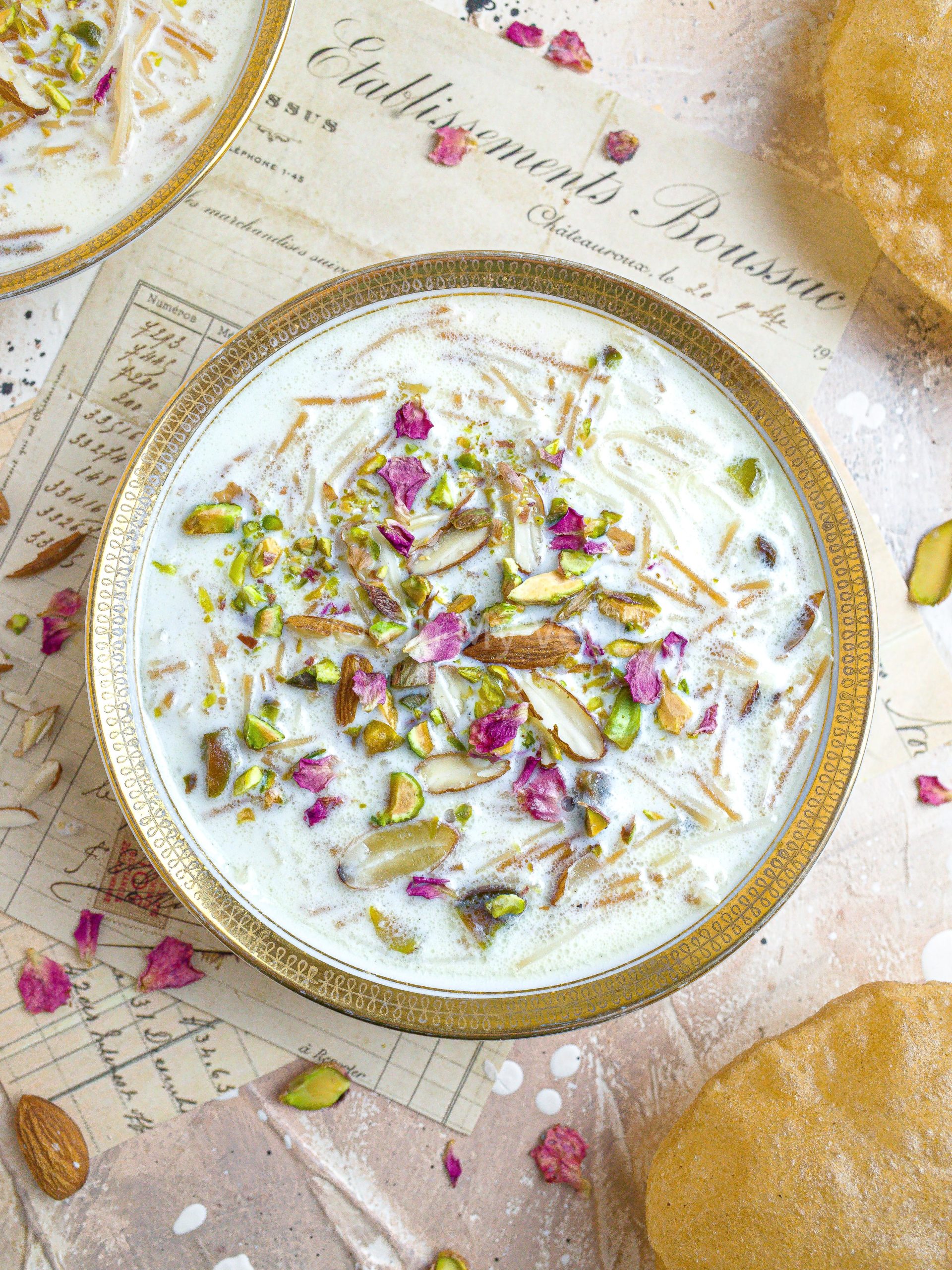 Seviyan kheer topped with rose petals in a white and gold bowl, on a vintage background.