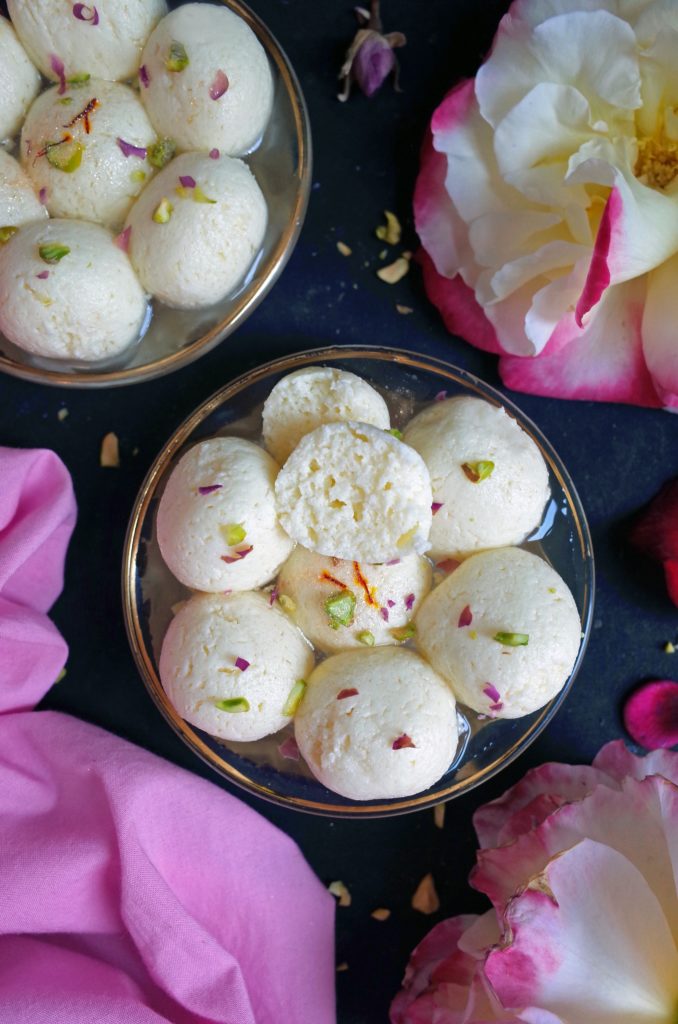Close up of Bengali spongy rasgulla topped with pistachio and saffron with roses