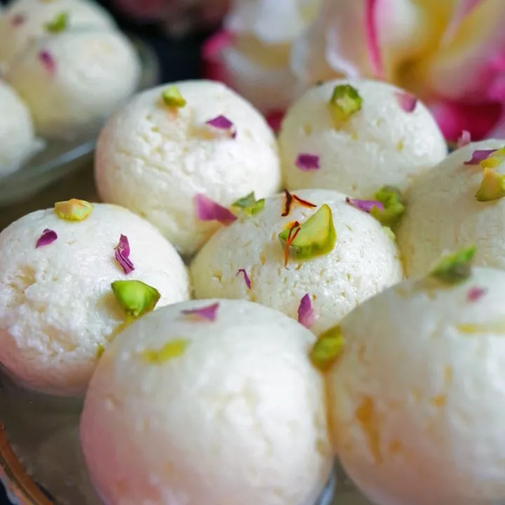Close up photo of Bengali Rasgulla in Cardamon, Rose and Saffron Sugar Syrup topped with Pistachios