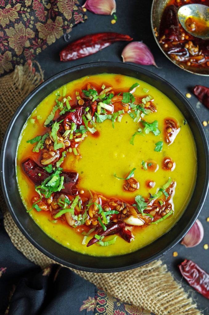 Dal Tadka in a black bowl with a spicy tempering on top and fresh coriander