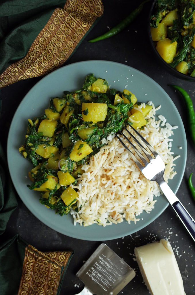 Aloo Palak / Saag Aloo on a blue plate with rice, coconut and a fork