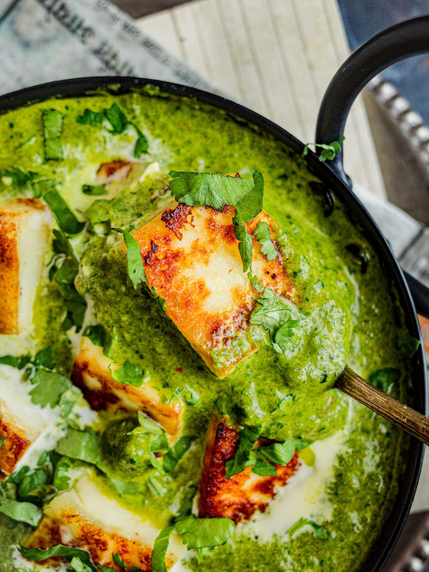 Close up picture of Indian palak paneer in a black bowl.