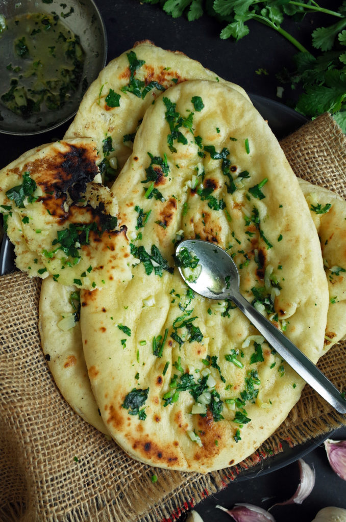 A pair of Indian Garlic and Coriander Herbed Naan Bread with a metal spoon