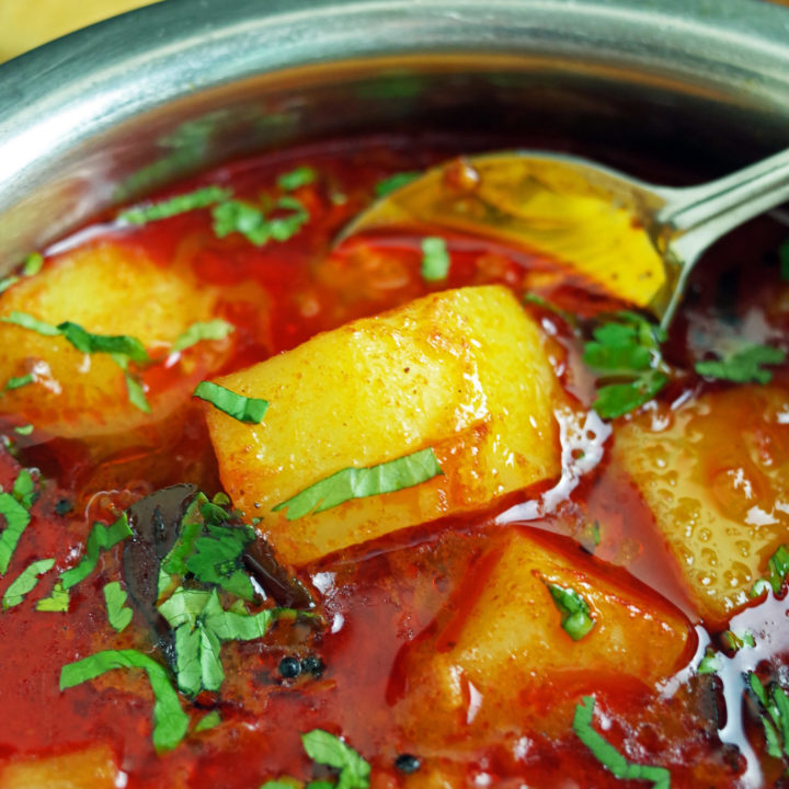 Maharashtrian Batata Rassa / Potato Curry in a steel bowl topped with fresh coriander