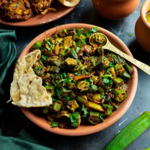 Vegan Bhindi Masala in a clay bowl with Chapati on a black background
