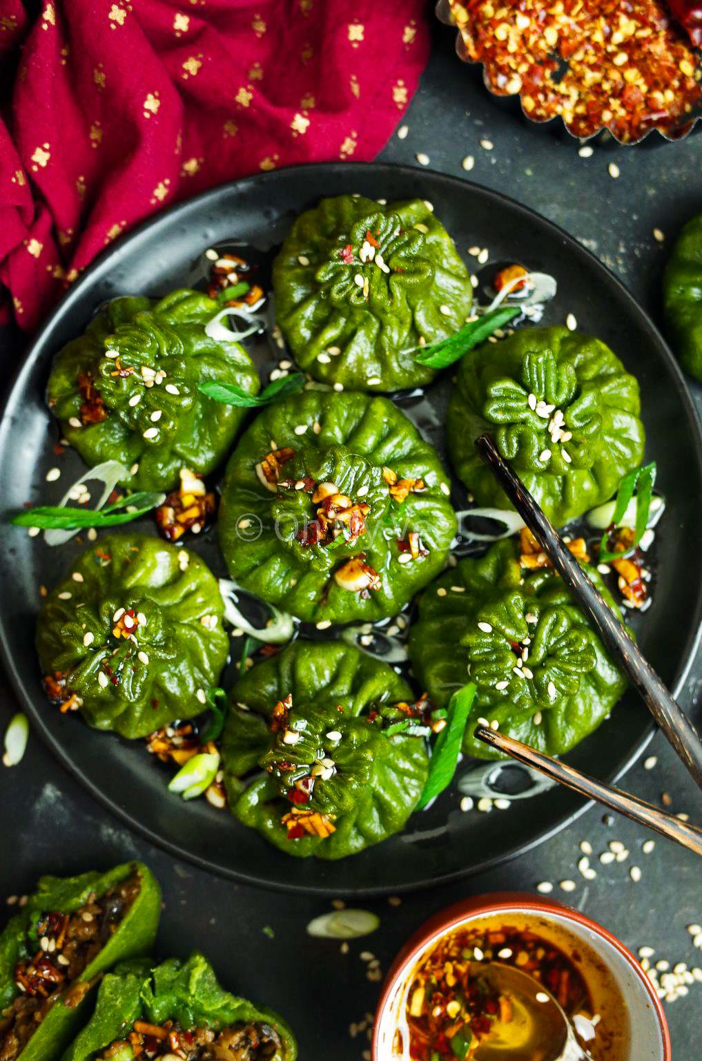 Spinach, Mushroom & Soy Chunk Potstickers on a black plate with dipping sauce