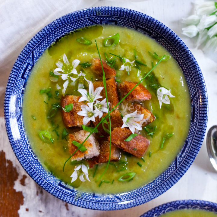 Vegan Leek Soup with Three Cornered Leek Oil, Croutons, and edible flowers in a blue bowl