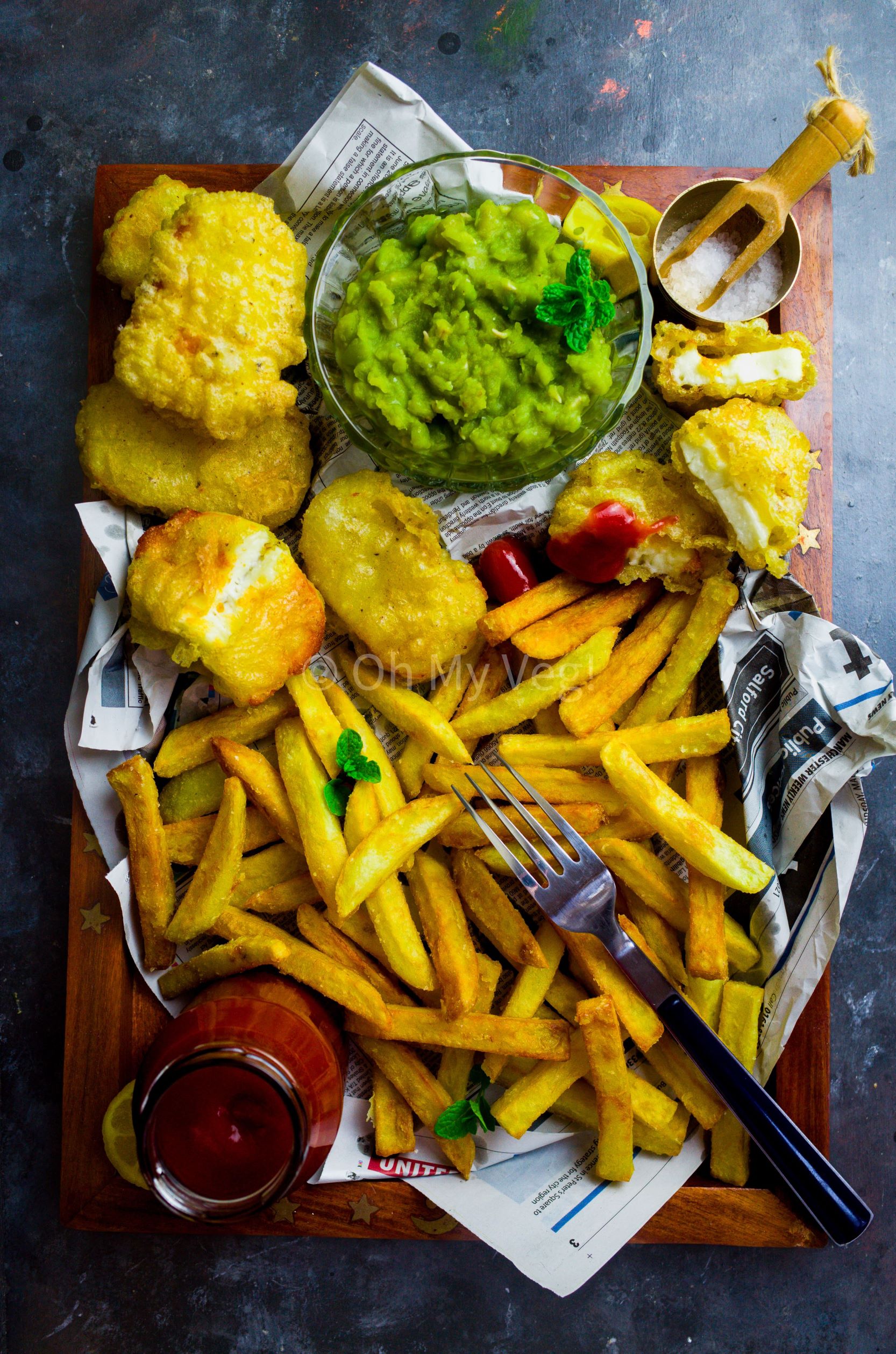 A tray with homemade chips, halloumi fish, mushy peas and ketchup
