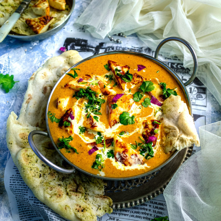 Shahi paneer in a silver kadai with naan bread