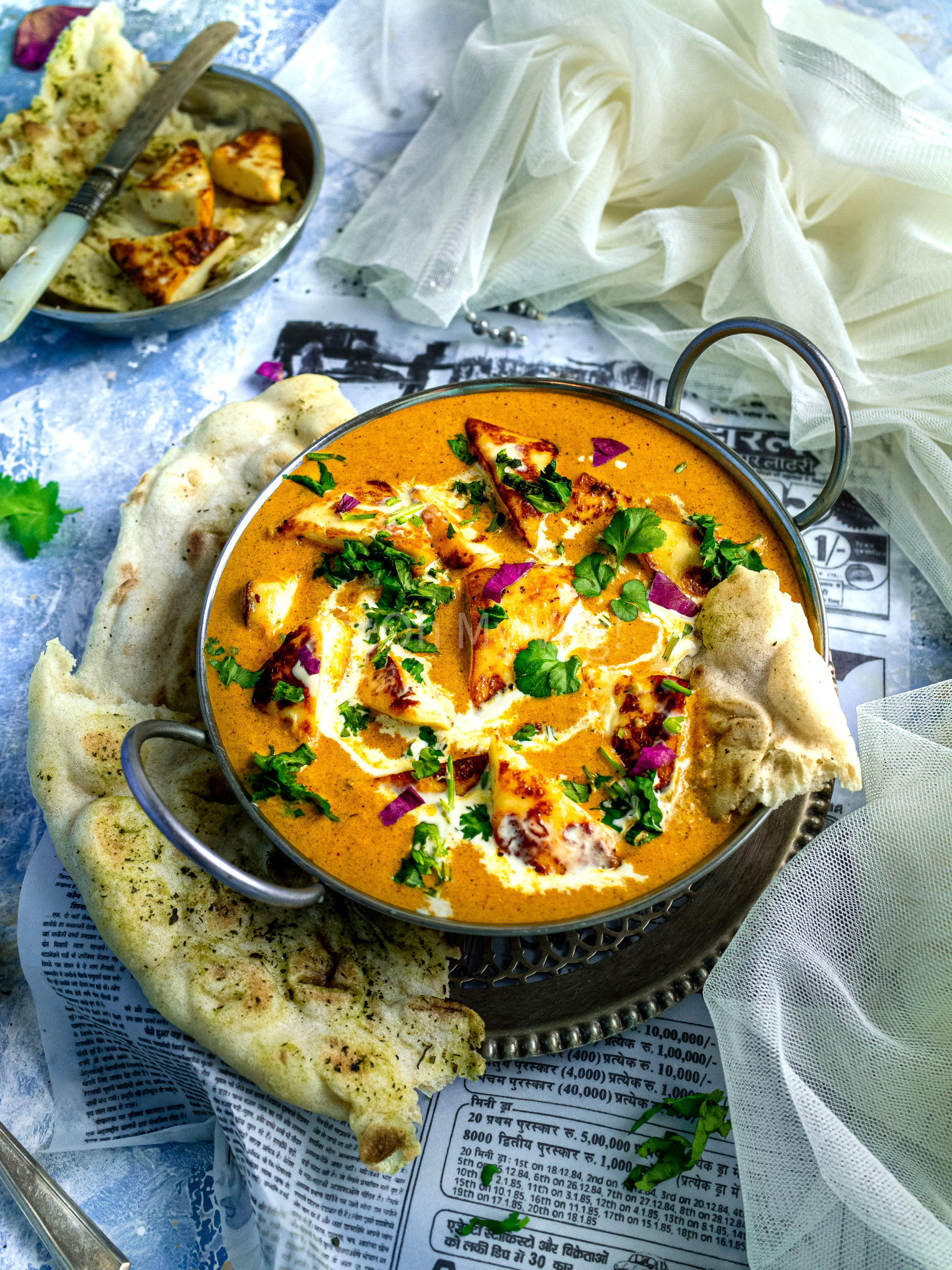 Shahi paneer in a silver kadai with naan bread