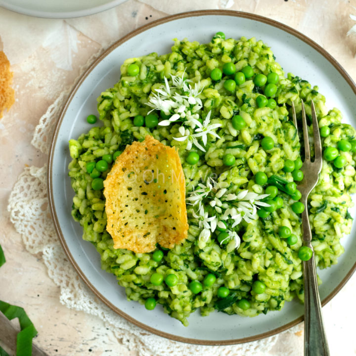 Wild garlic and pea risotto with cheddar tuiles on a white plate