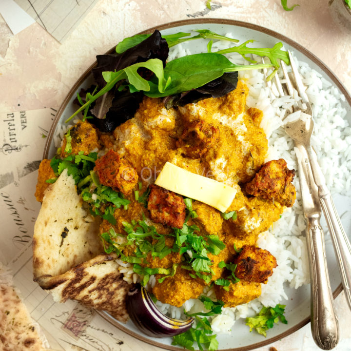 Vegetarian butter chicken on a plate with rice, salad and naan.