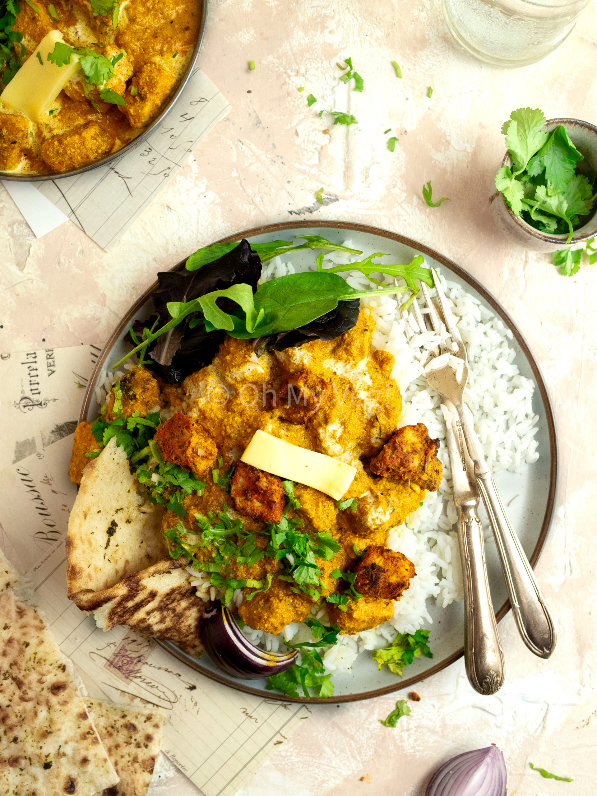 Vegetarian butter chicken with rice, naan, and salad on a plate