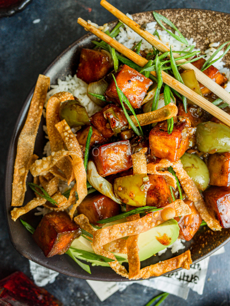 Chili paneer in a bowl with wonton crisps.