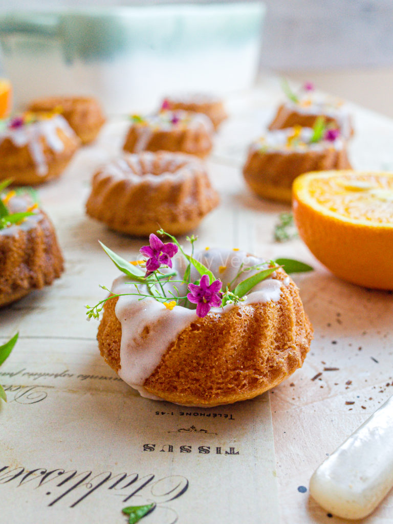 Mini bundt cake flavored with orange and cardamom from the side, topped with jasmine flowers. 