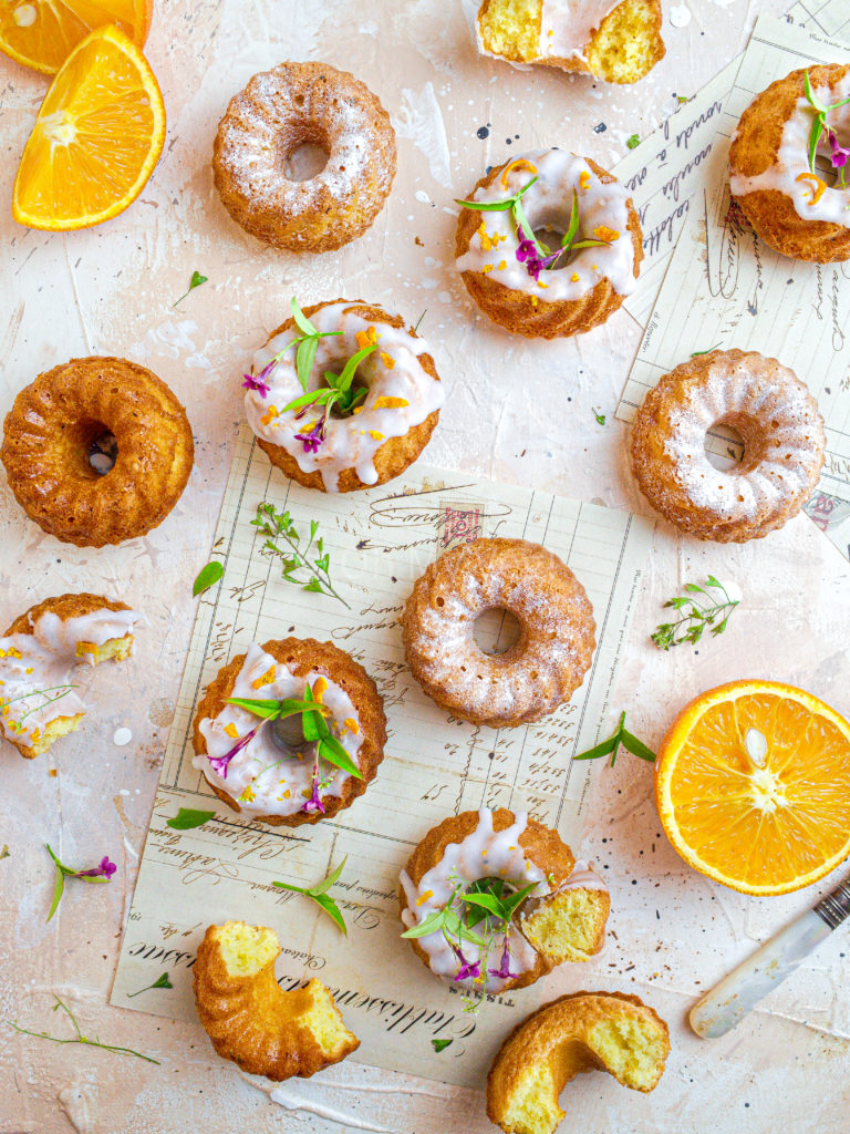 Mini orange and cardamom bundt cakes with orange halves.