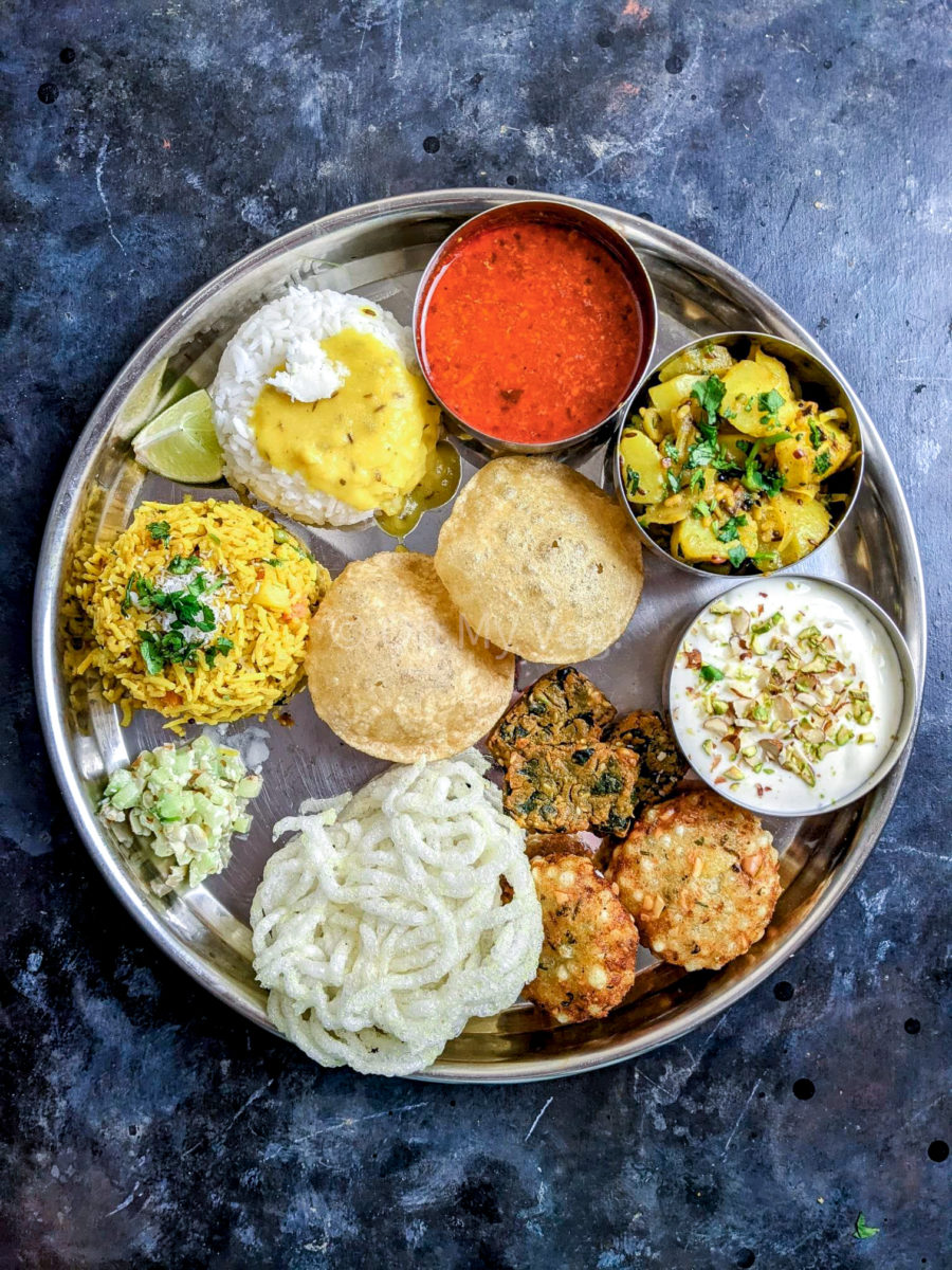 Maharashtrian Thali including: Masale Bhaat, Varan Bhaat, Tomato Saar, Batata Bhaji, Shrikhand Puri, Sabudana Vada, Palak Vadi, Kurdai, and Khamang Kakri