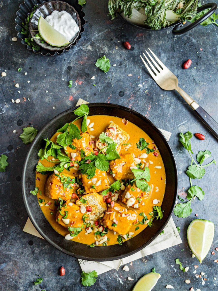 A bowl of tofu satay curry on a dark background. 