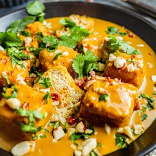 Creamy vegan tofu satay curry in a black bowl.