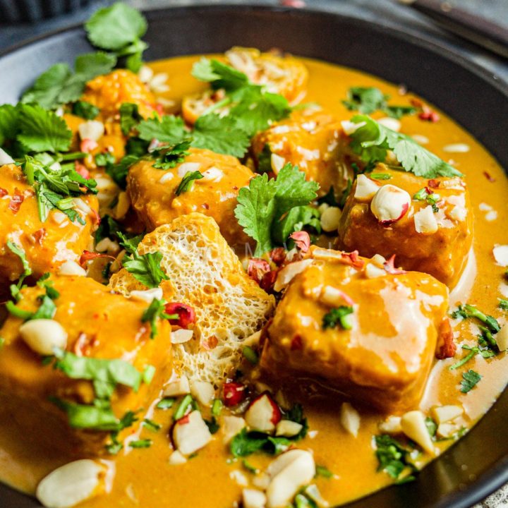 Creamy vegan tofu satay curry in a black bowl.