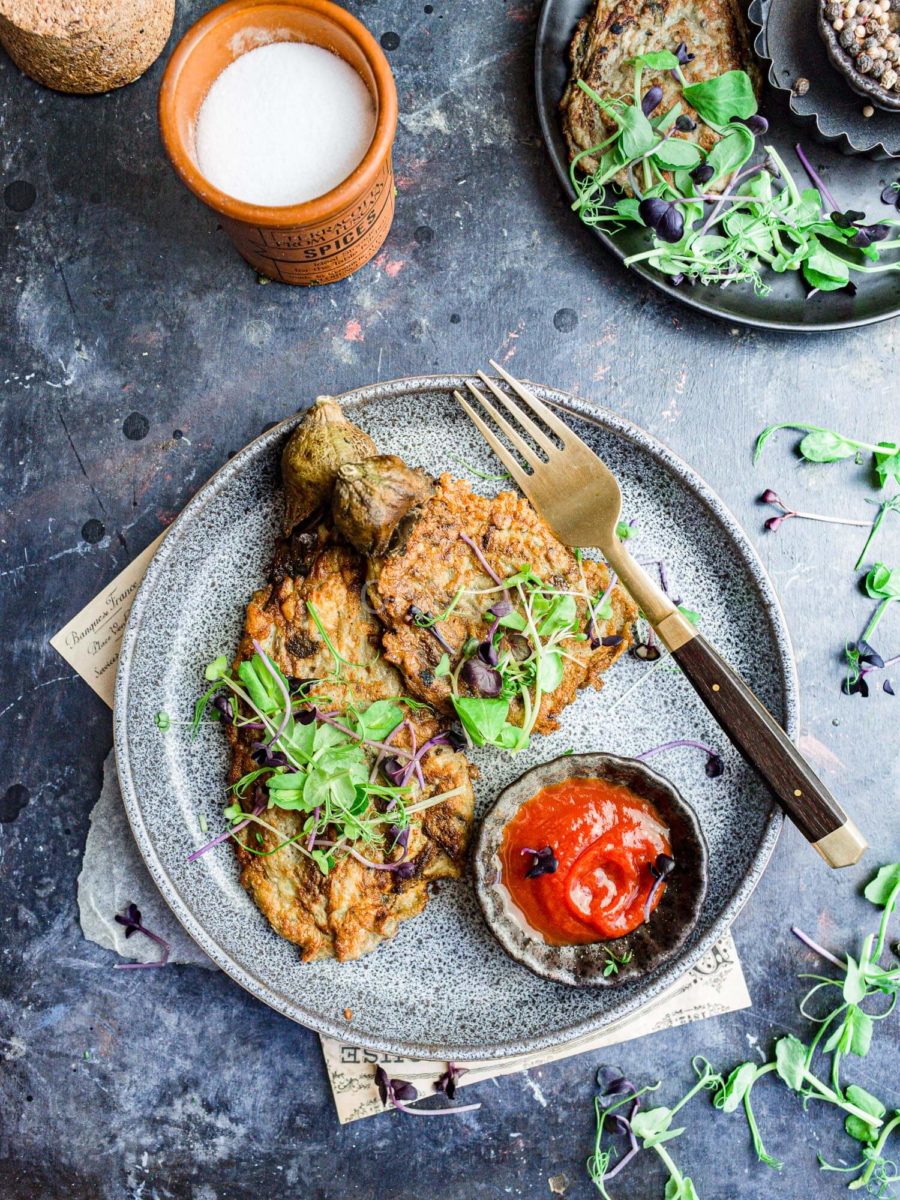 Tortang talong on a plate with banana ketchup, cress, and a fork. 