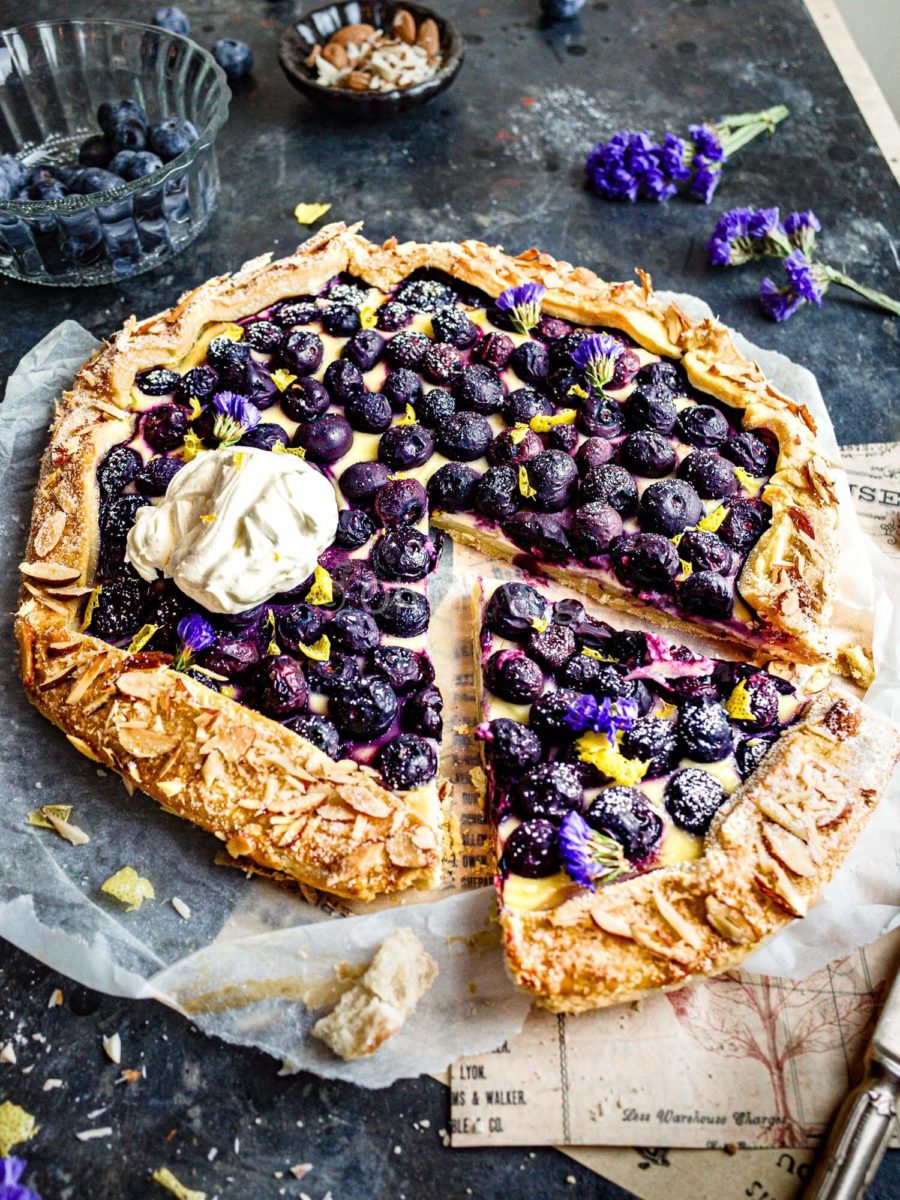 Blueberry cheesecake galette with a slice cut out and lemon zest on top. 