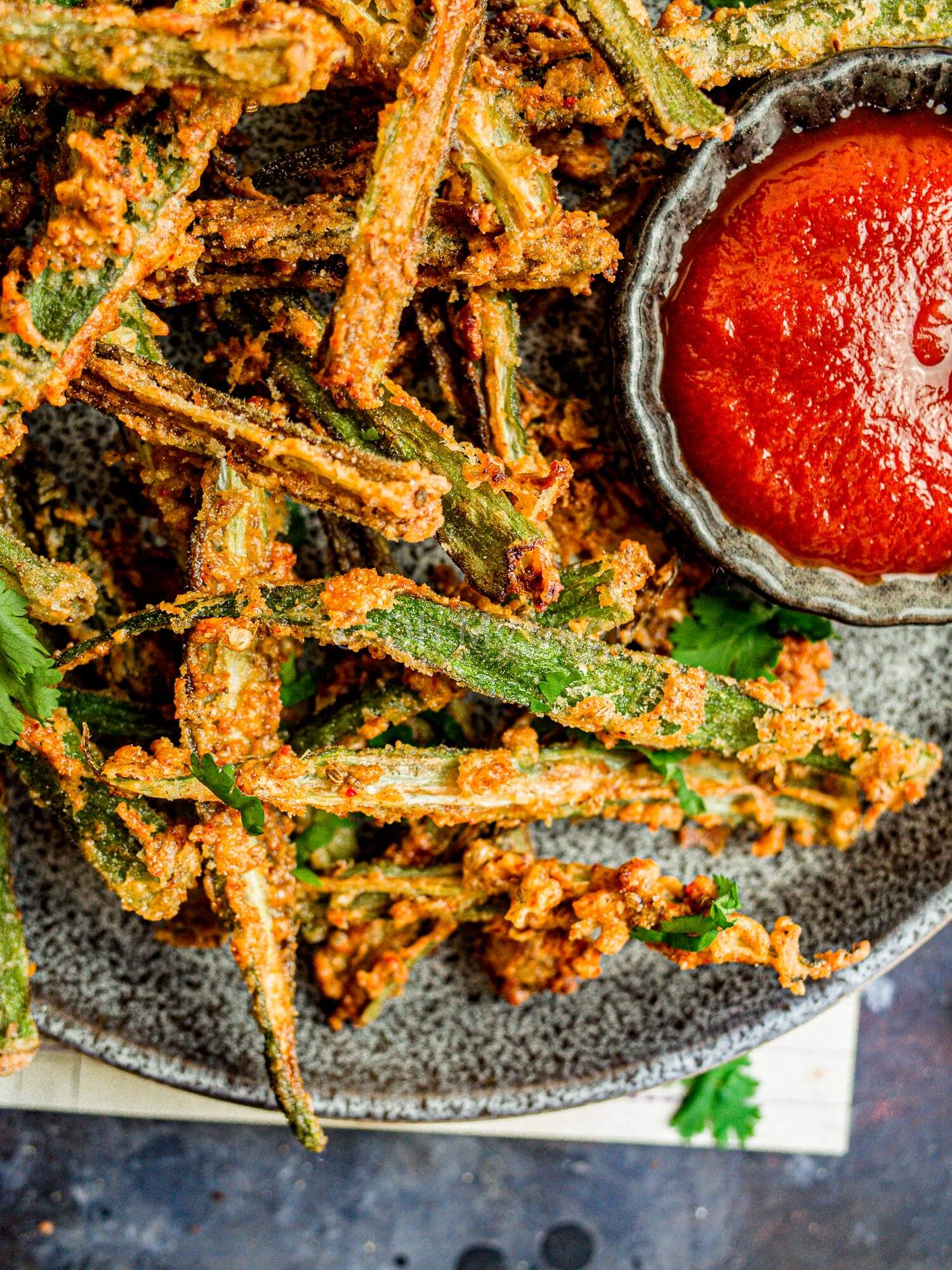 Vegan okra fries or Indian kurkuri bhindi on a plate with ketchup.