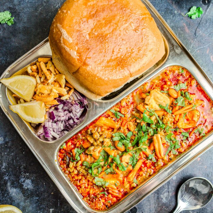 Misal pav on a plate with farsan and onion.