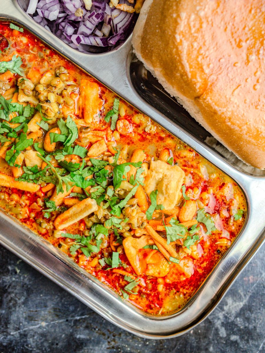 Misal pav on a steel plate, topped with farsan and coriander. 