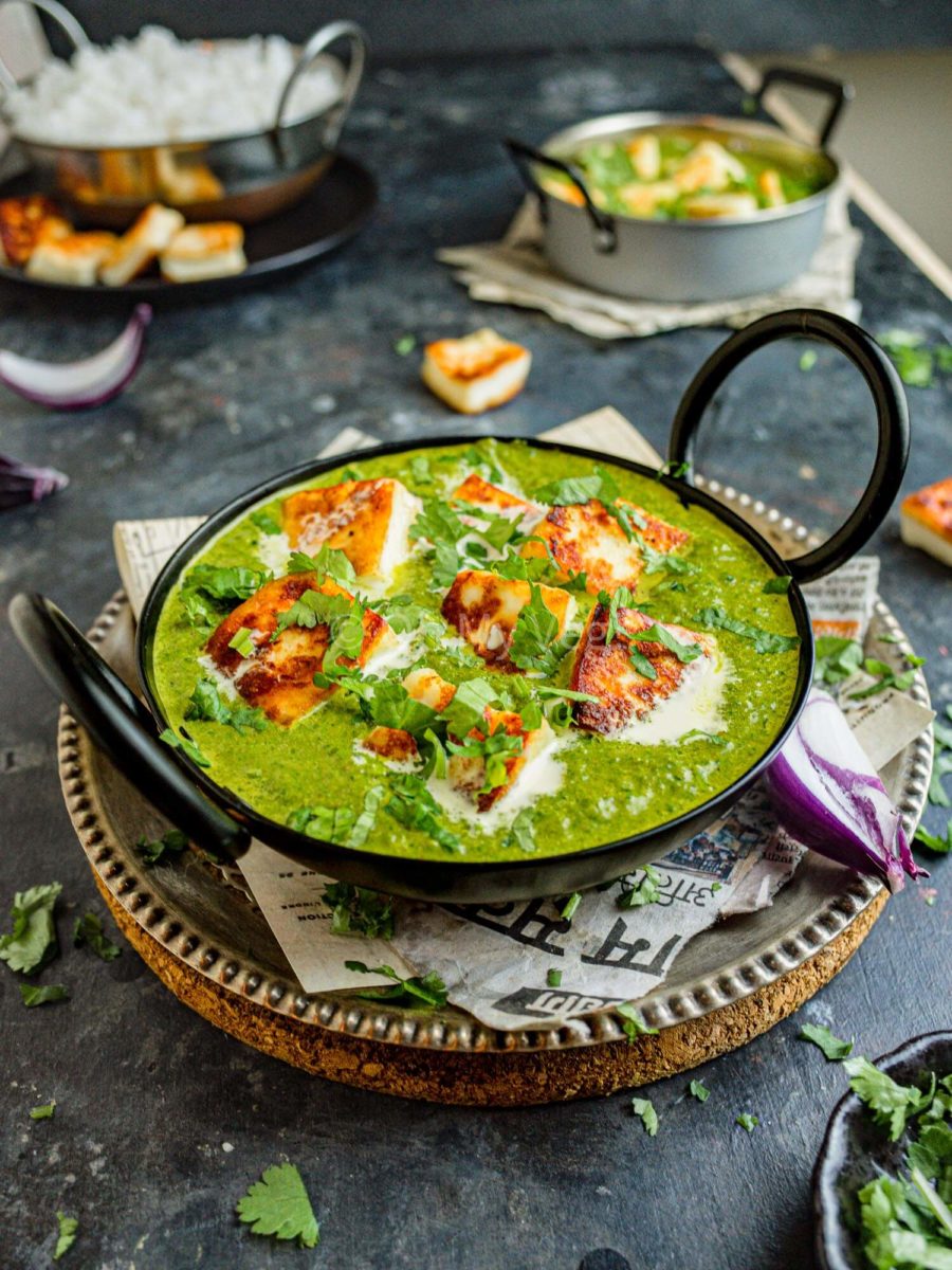 Spinach curry with Indian cheese, palak paneer in a black bowl. 