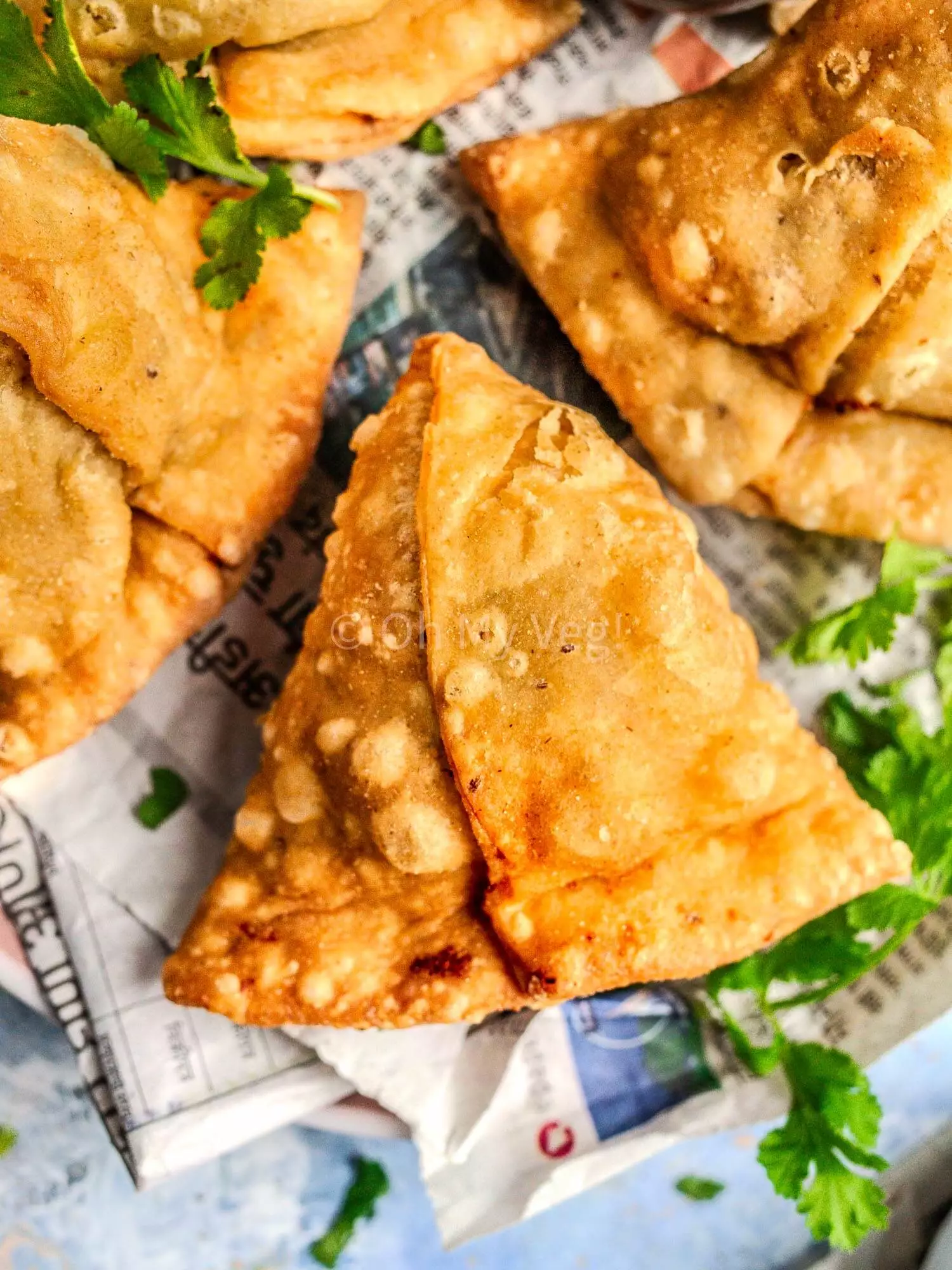 Vegan vegetable samosa on newspaper.