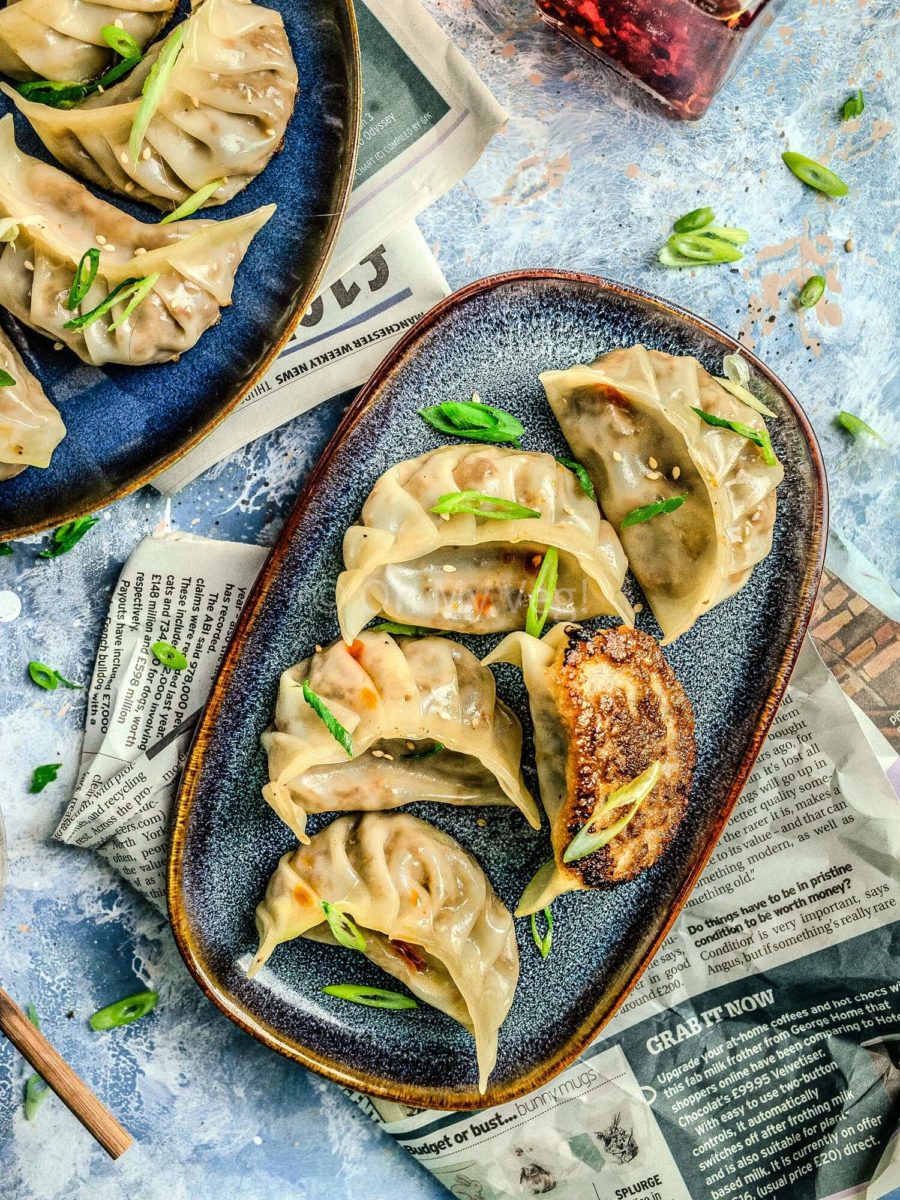 Vegetable potstickers on a blue side plate with spring onions.