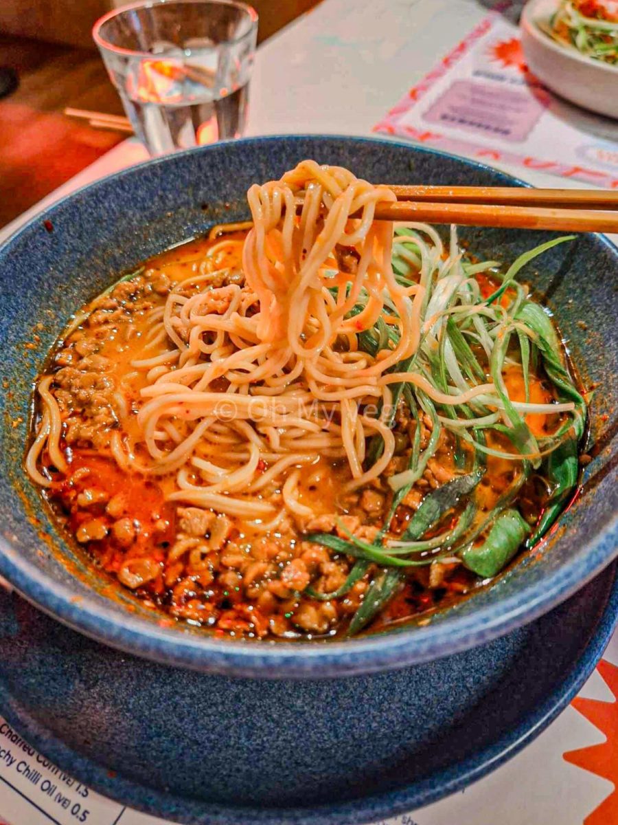 Chopsticks holding noodles in the spicy miso tantanmen ramen