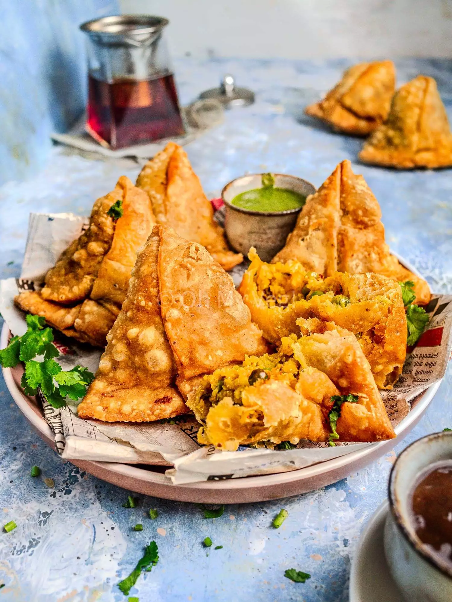 Homemade Punjabi samosas on a plate with green chutney. 