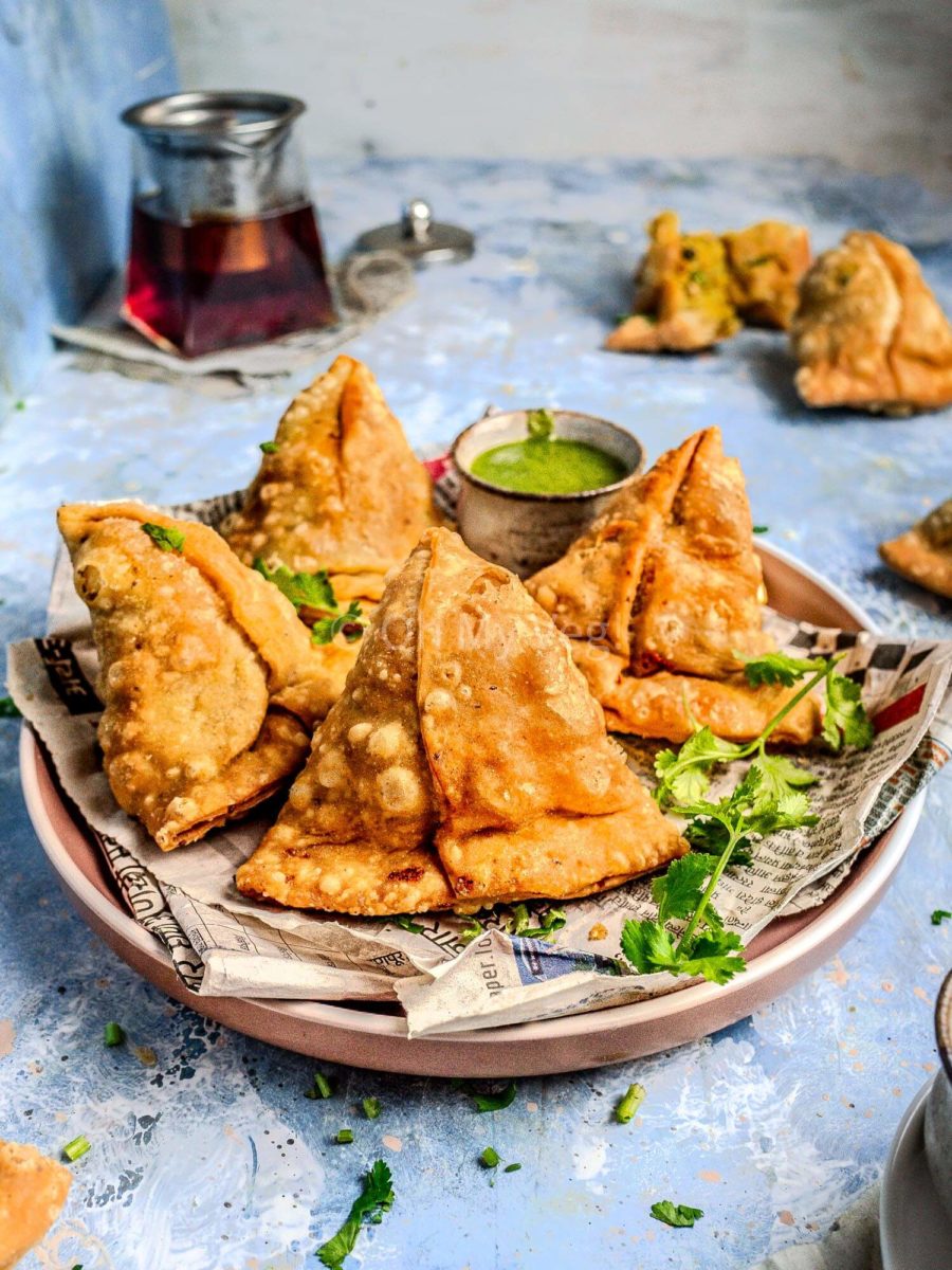 Vegetable samosa on a plate with green chutney.