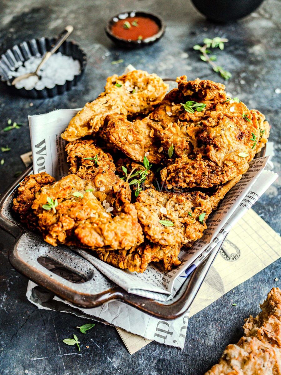 A platter of vegan fried chicken on top of newspaper. 