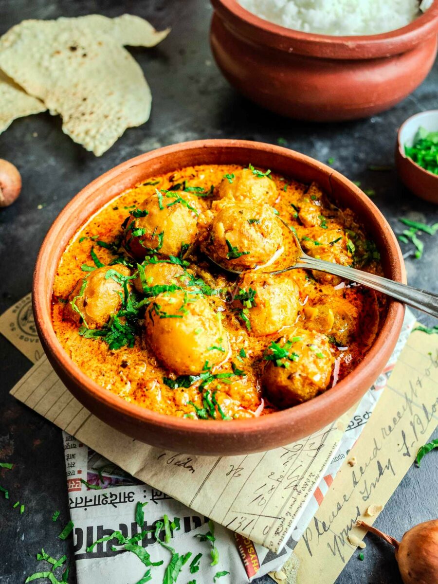Vegetarian dum aloo in a clay bowl with a spoon. 