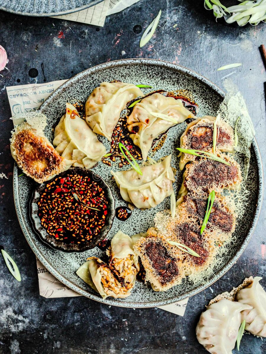 Tofu potstickers on a plate with sauce. 