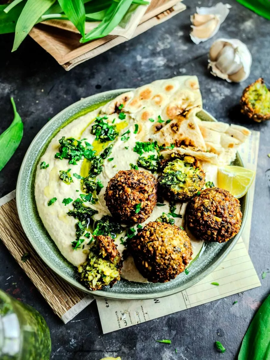 Wild garlic falafel on top of vegan hummus, on a plate with naan. 