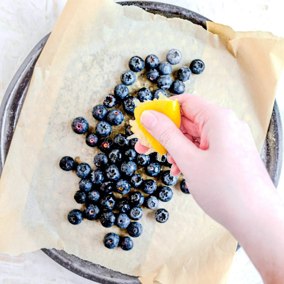 Squeezing lemon over blueberries.