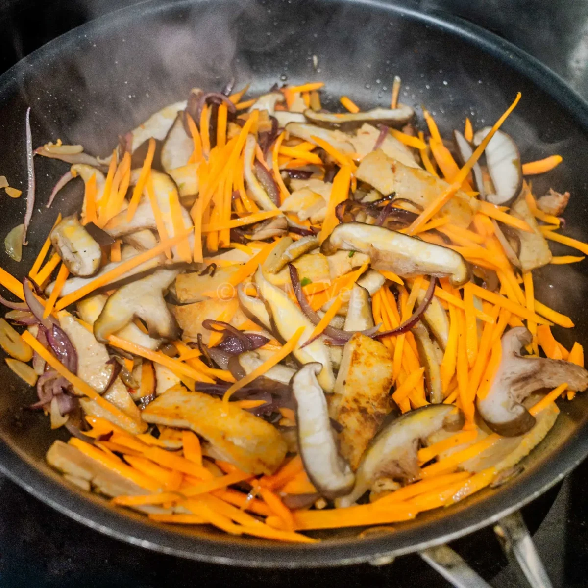 Stir-frying carrot and mushrooms.