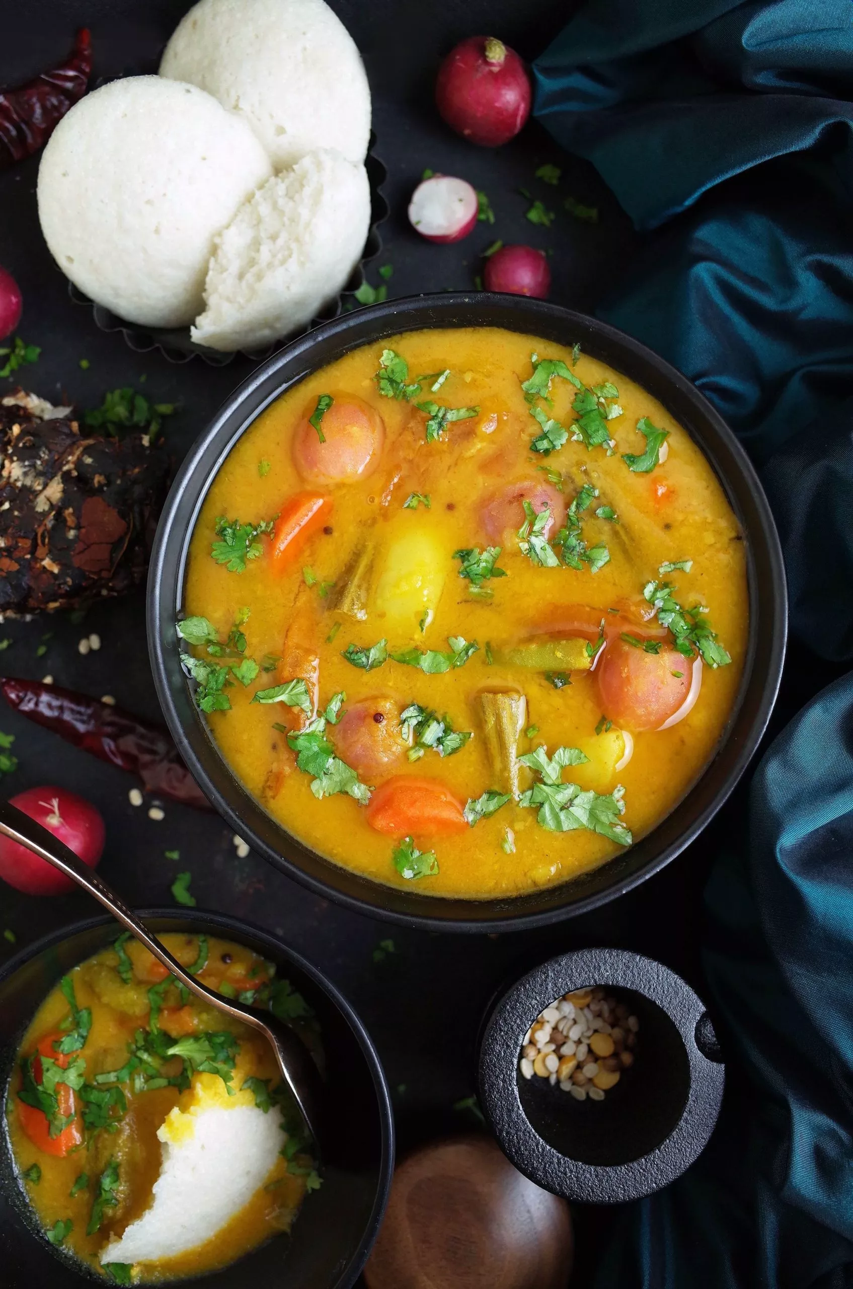 South Indian Vegetable Sambar in a black bowl with Idli