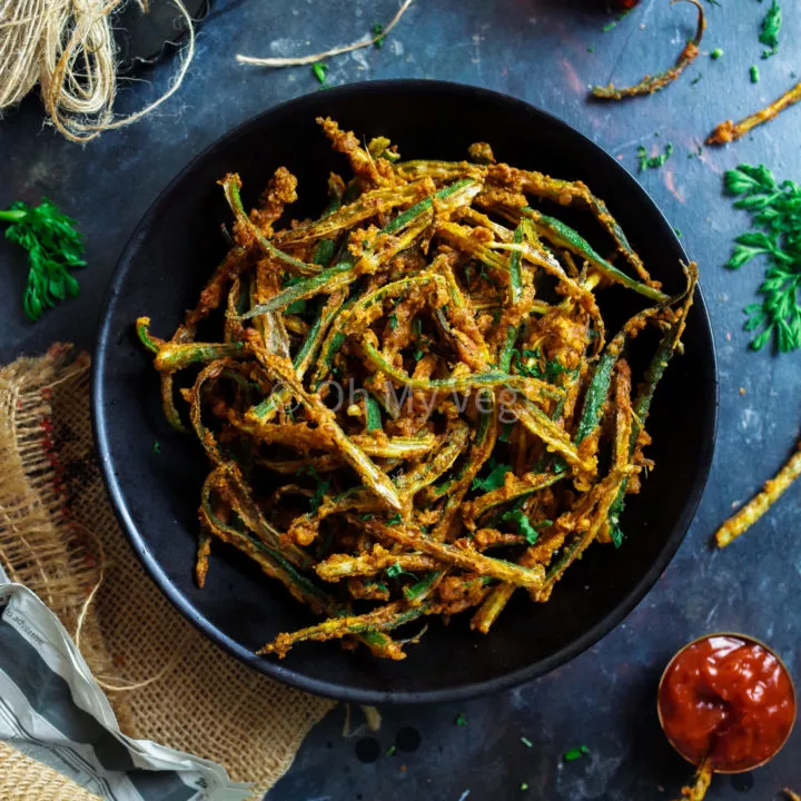 Indian Kurkuri Bhindi (Spicy Okra Fries) in a bowl bowl on a blue background