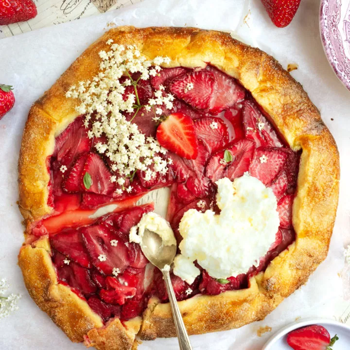 Strawberry and elderflower galette topped with whipped cream and a slice taken out