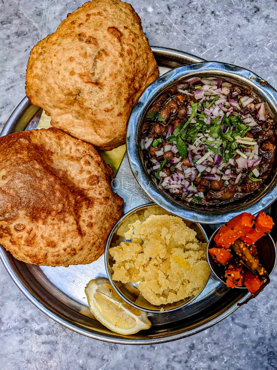 A thali with chole, sooji halwa, puri, carrot pickles, and a slice of lemon from Dishoom Carnaby. 