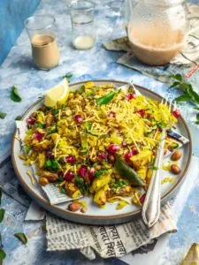 Maharashtrian kanda batata poha on a plate with a teapot in the background