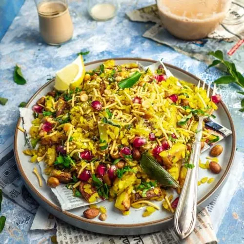 Maharashtrian kanda batata poha on a plate with a teapot in the background