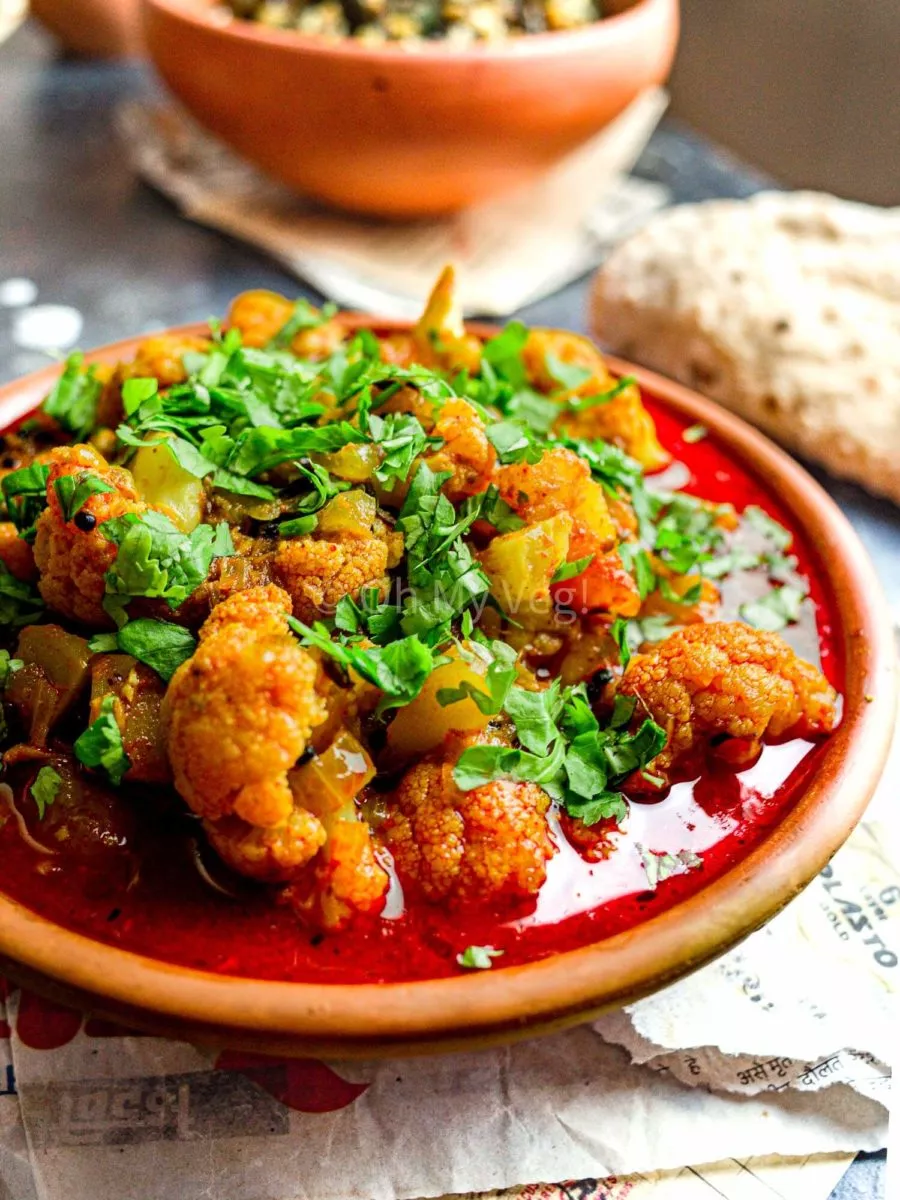 Cauliflower in an oily Maharashtrian Flower Batata Rassa gravy, with a chapati in the background. 