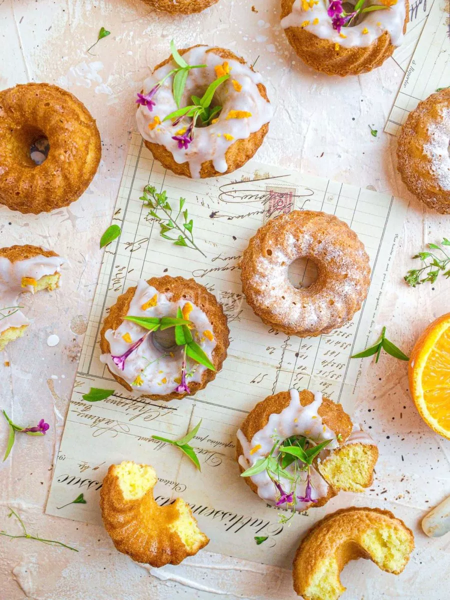 Mini orange and cardamom bundt cakes topped with glaze and icing sugar.