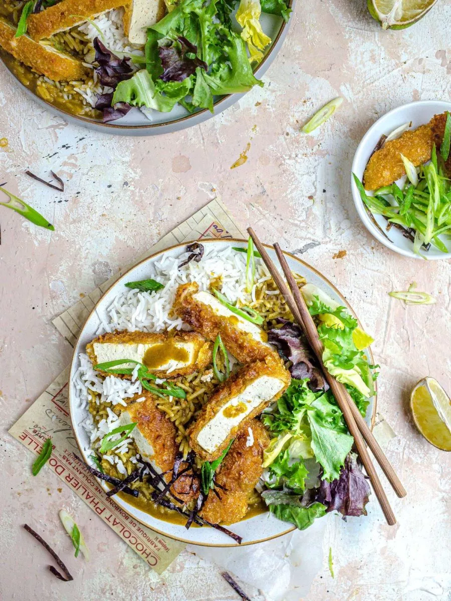 Katsu curry with tofu and salad on a plate with chopsticks.